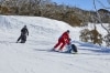 Two people with limited mobility adaptive skiing with instructors down a snow-covered mountain in Thredbo, Snowy Mountains, New South Wales © Tourism Australia
