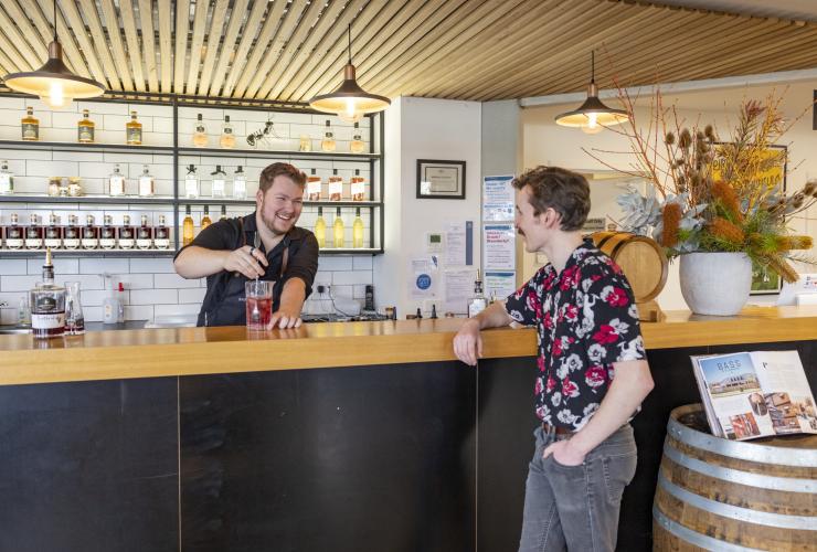 Man laughing with a bartender as he prepares a cocktail at Bass & Flinders Distillery, Mornington Peninsula, Victoria © Tourism Australia