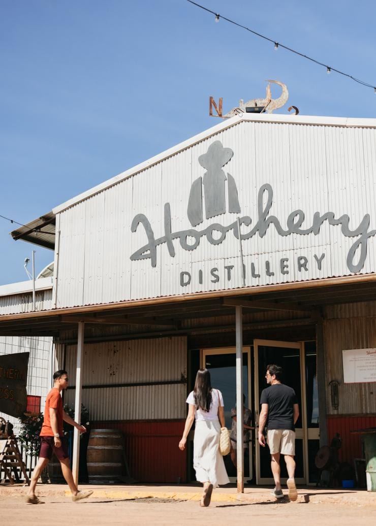 Three people walking into the large tin shed of the Hoochery Distillery Café, Kununurra, Western Australia © Tourism Western Australia