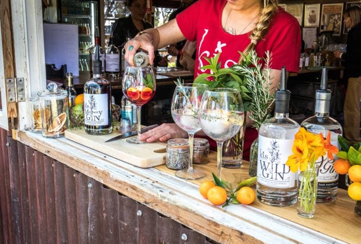 Close up of a bartender pouring a fruity cocktail on a bar surrounded by fresh fruit, herbs and bottles of gin at Kangaroo Island Spirits, Kangaroo Island, South Australia © South Australian Tourism Commission