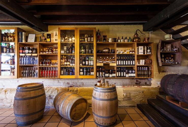A wide range of spirits on display in a room filled with wooden shelves and barrels at Lark Distillery, Hobart, Tasmania © Tourism Tasmania/Nick Osborne