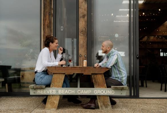 A couple enjoying drinks at a picnic table outside Gurney's Cidery, Gippsland, Victoria © Tourism Australia