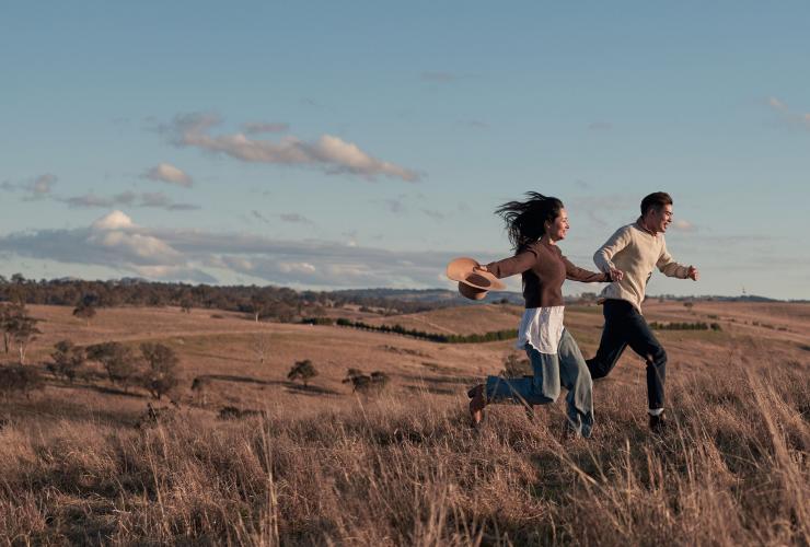 Couple running through the pasture at Wilga Station, Evans Plains, New South Wales © Destination NSW