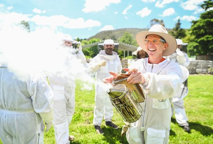 Beekeeper using a smoker to calm bees at Bowral Beekeeping, Southern Highlands, New South Wales © Tourism Australia