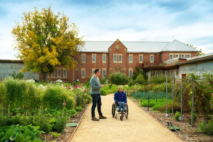 A woman in a wheelchair enjoys a garden tour at The Agrarian Kitchen, Southern Tasmania, Tasmania © Tourism Australia