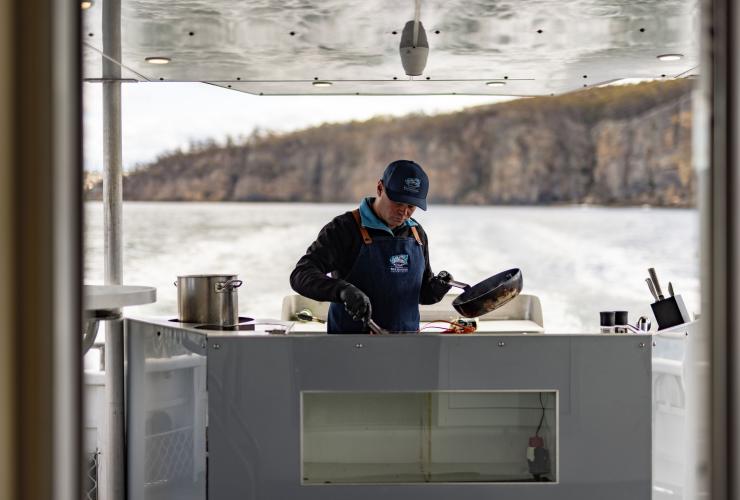 Man cooks seafood on the back of a boat during a tour with  Tasmanian Wild Seafood Adventures, Hobart, Tasmania © Dearna Bond