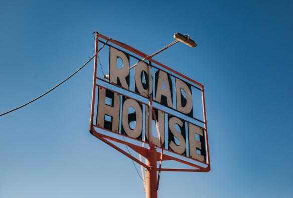 Angle looking up towards a sign reading "Road House" in a clear blue sky at Pink Roadhouse, Flinders Ranges & Outback, South Australia © South Australia Tourism Commission