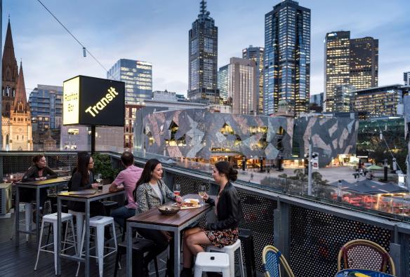 Two women enjoy drinks with views of the Melbourne skyline at Transit Rooftop Bar, Melbourne, Victoria © Visit Victoria 