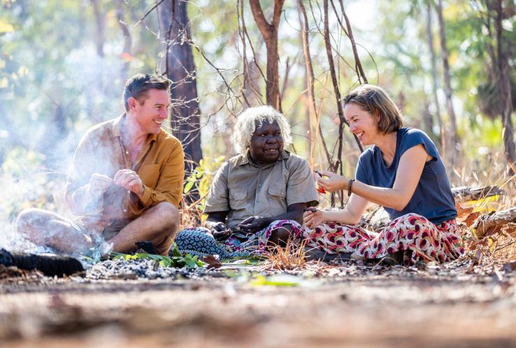 A couple seated on a mat among bushland with an Aboriginal Guide, Animal Tracks Safari, Kakadu National Park, Northern Territory © Tourism NT/Helen Orr