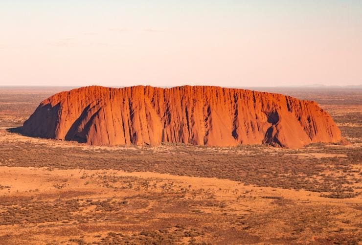 Aerial view over a giant red rock monolith in an outback landscape, Uluṟu, Uluṟu-Kata Tjuṯa National Park, Northern Territory © Tourism Australia/Nicholas Kavo