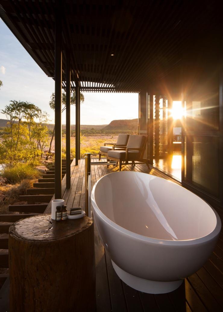 A porch with an outdoor bath and lounge chairs surrounded by nature during sunset at El Questro Homestead, El Questro Wilderness Park, Western Australia © Timothy Burgess