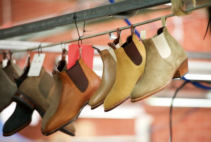 A row of luxury leather boots hanging from a rack, RM Williams Tour, The Tailor, South Australia © Cormac Hanrahan
