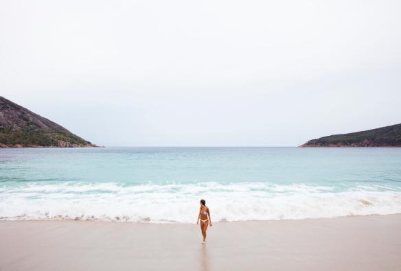 Woman emerging from the ocean onto white sand at Wineglass Bay Beach, Freycinet National Park, Tasmania © Sean Scott