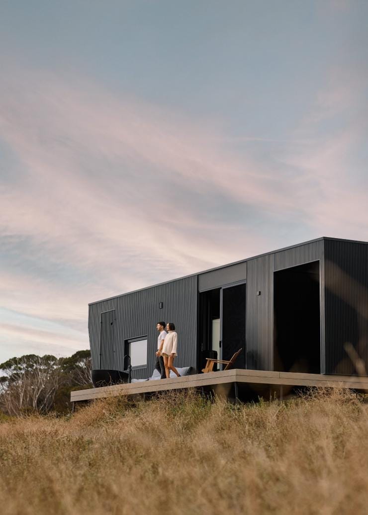 A couple walking onto a balcony of a sleek tiny home in a grassy pasture, Cabn, Kangaroo Island, South Australia © South Australian Tourism Commission