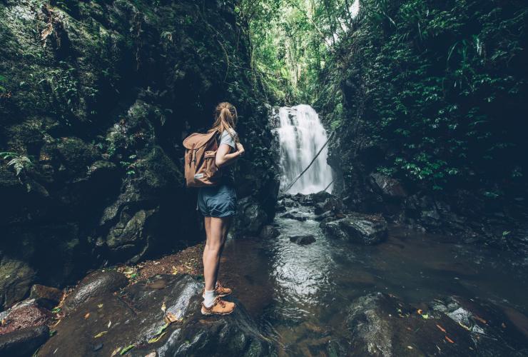 A girl standing with a backpack at the edge of Box Log Falls in Lamington National Park, Queensland © Tourism and Events Queensland