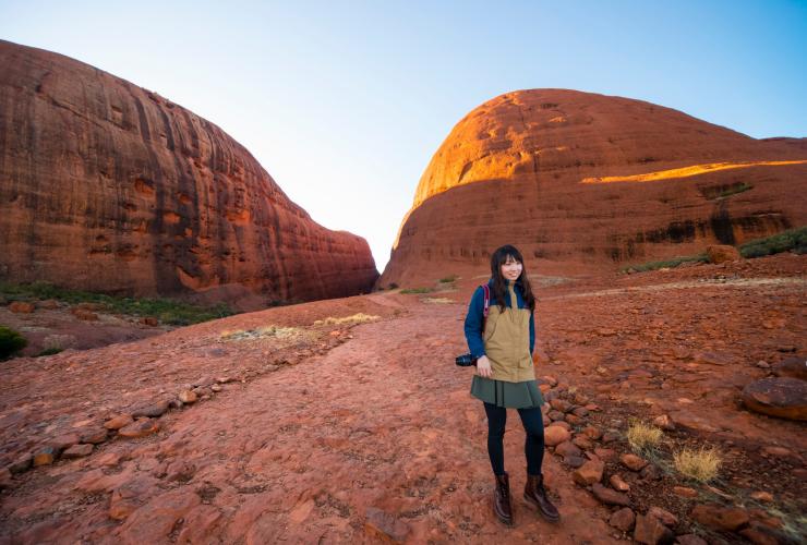 A woman posing in from of two towering cliffs along the Valley of the Winds walk, Kata Tjuta, Red Centre, Northern Territory © Tourism NT/Salty Aura
