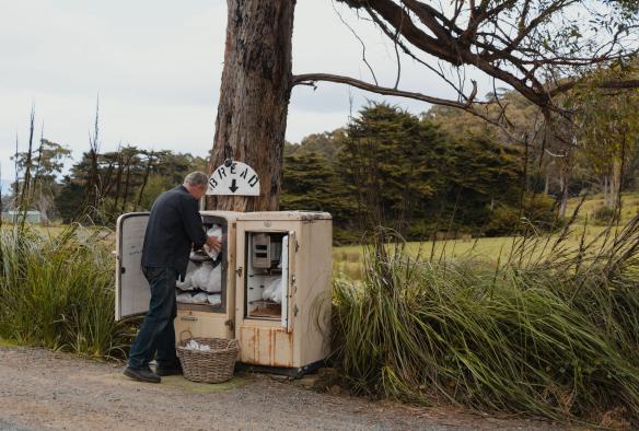 A man collecting bread from a small roadside stall on Bruny Island, Tasmania © James Vodicka