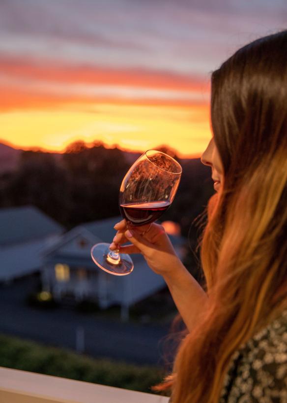 Woman enjoying the sunset and a glass of wine at Nimbo Fork Lodge, Killimicat, New South Wales © Destination NSW