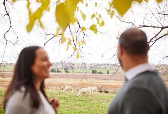 Couple watching sheep roam around at Bathurst Grange Distillery, Bathurst, New South Wales © Destination NSW