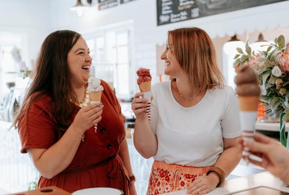 Two woman smile as they enjoy ice cream cones from Bodalla Dairy, South Coast, New South Wales © Destination NSW
