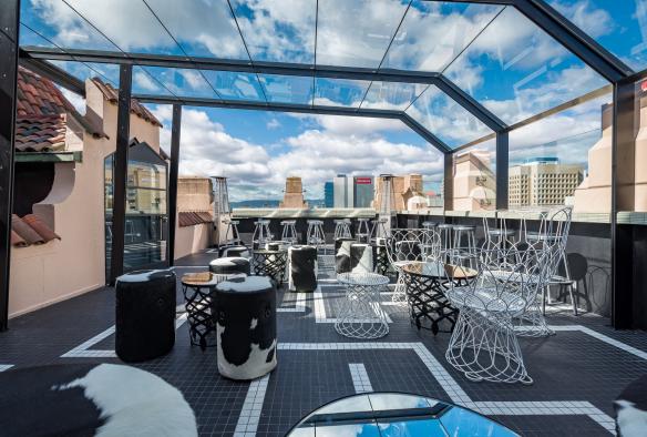 A stylish rooftop bar with a glass awning overlooking city buildings at Hennessy Bar, Adelaide, South Australia © Tourism Australia