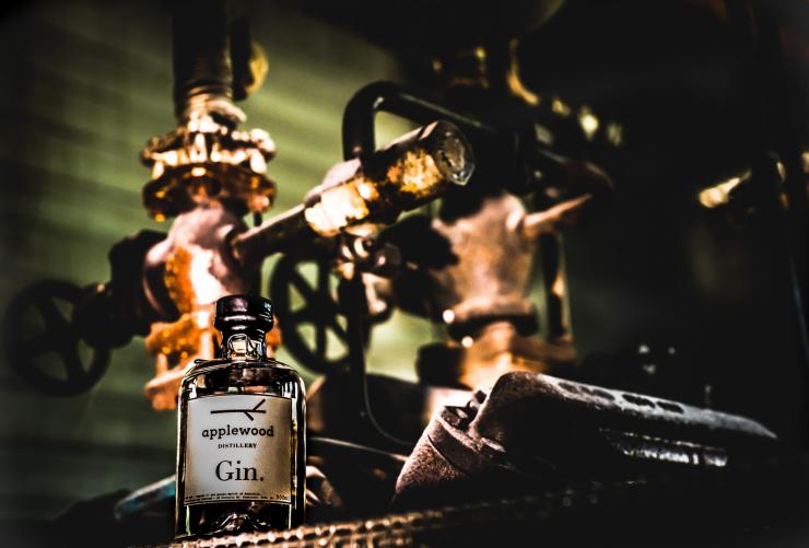 Close up of a bottle of gin with distilling equipment in the background at Applewood Distillery, Adelaide Hills,South Australia © Applewood Distillery