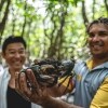 An Indigenous guide holding up a mud crab as a tour participant smiles widely behind him, Walkabout Cultural Adventures, Daintree Rainforest, Queensland © Tourism and Events Queensland