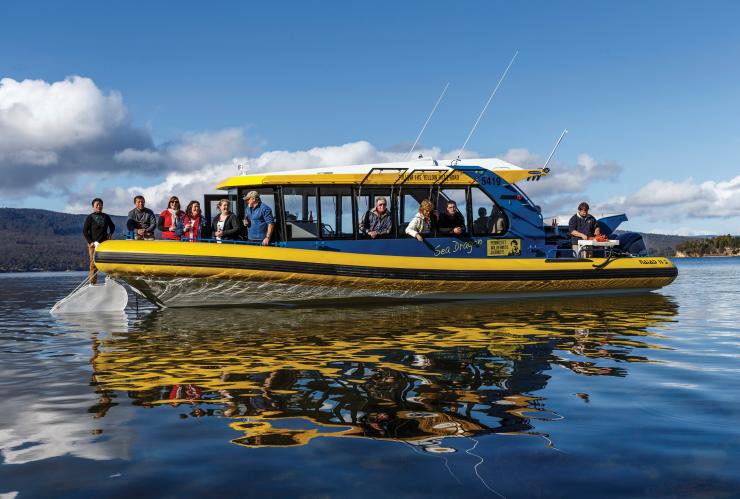 A boat on calm waters with people drinking beer and looking out at the view, Tasmanian Seafood Seduction, Hobart, Tasmania © Tourism Tasmania