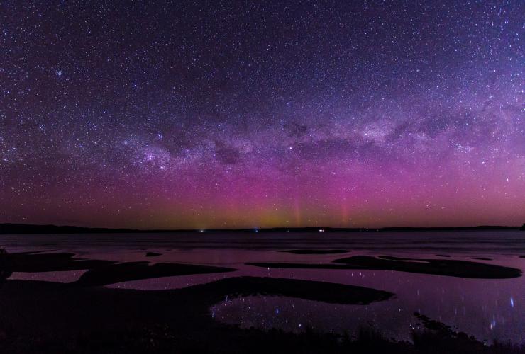 The Aurora Australis lighting up the night sky in pink and purple over snaking bodies of water at Strahan, Tasmania © Dietmar Kahles