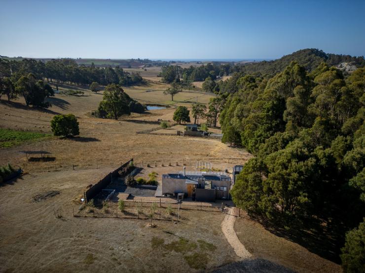 Aerial view over a tiny house in a paddock sprinkled with trees, Compass Hut, Devonport, Tasmania © Tourism Tasmania