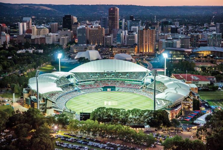 Aerial view over a stadium in a city with a large green field and crowds filling the stands at Adelaide Oval, Adelaide, South Australia © Hiro Ishino Photography