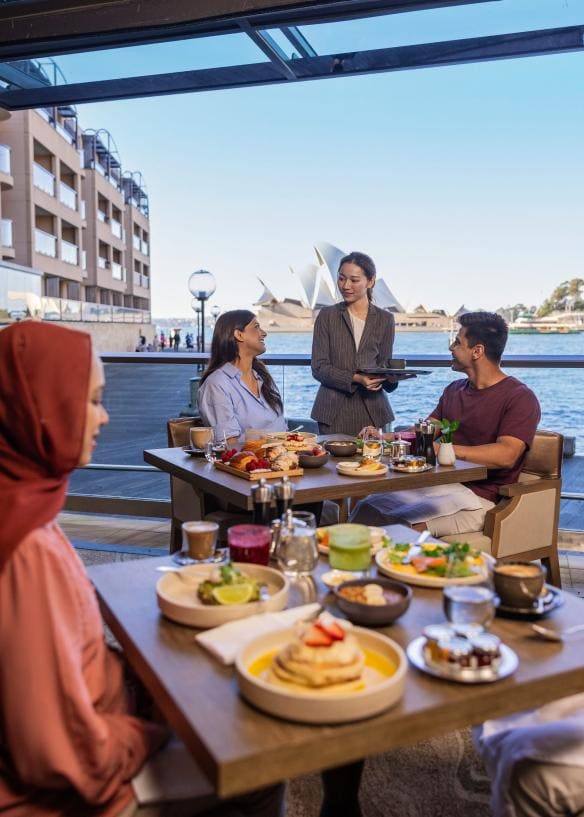 Tables of people dining on breakfast dishes and coffee with a view overlooking the Sydney Opera House at Park Hyatt, Sydney, New South Wales © Tourism Australia 