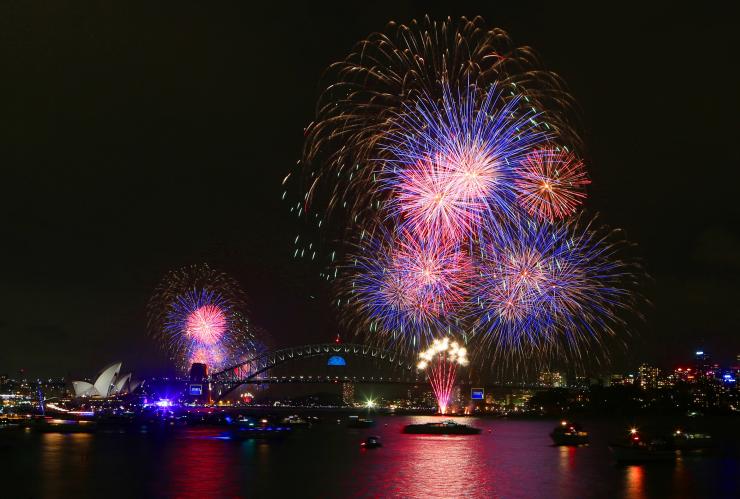 Colourful fireworks erupting in a night sky over boats on a city harbour during New Year's Eve Fireworks, Sydney, New South Wales © Tourism Australia
