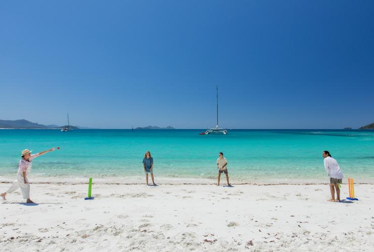 A family playing cricket on a white sand beach during a tour with Explore Group, Whitsundays, Queensland © Tourism Australia
