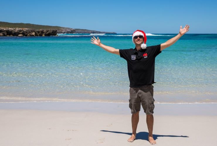 A person standing on a beach wearing a Christmas hat at Hanson Bay, Kangaroo Island, South Australia © Tourism Australia