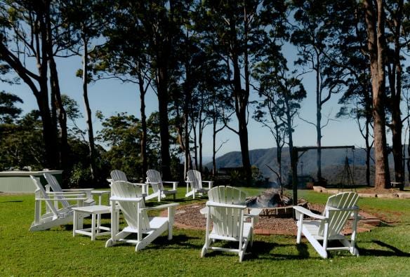 White lawn chairs around a firepit with trees in the background at Verandah House Country Estate, Tamborine Mountain, Queensland © Verandah House Country Estate