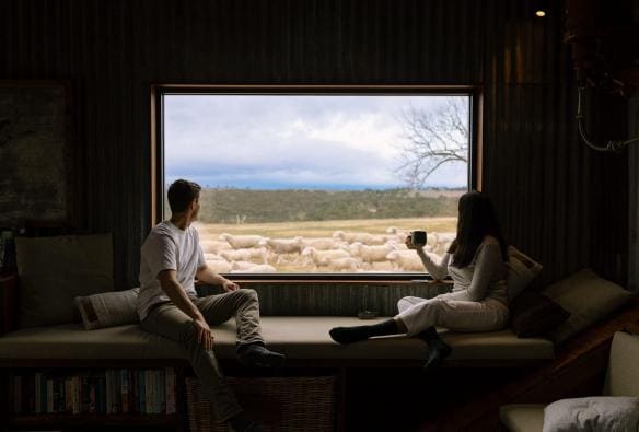 Couple watching sheep through a window at Wilga Station, Bathurst, New South Wales © Tourism Australia