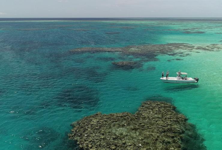 Aerial view over fishermen casting a line into clear turquoise ocean from a small boat, East Coast Angling, Great Barrier Reef, Queensland © East Coast Angling