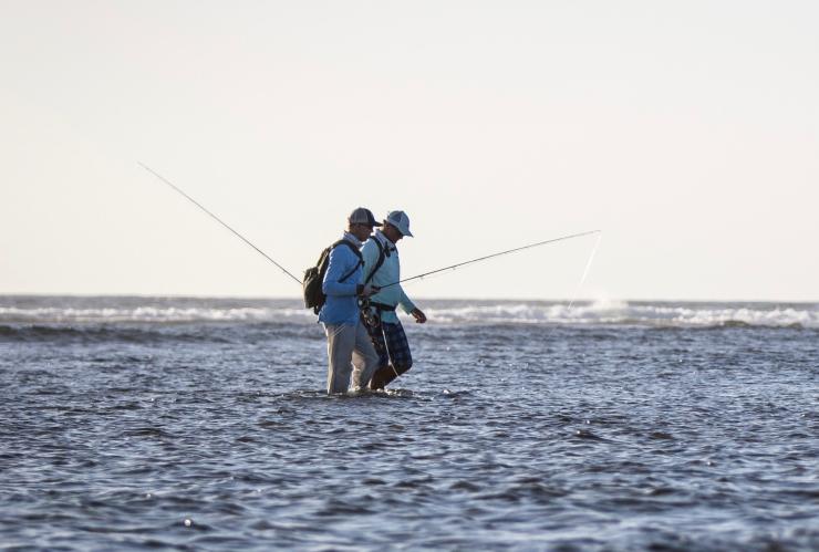 Two people wading in the ocean with fishing rods, Fly Fishing Frontiers, Exmouth, Western Australia © Joshua Hutchins