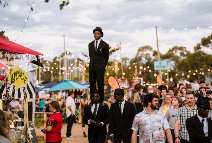A man standing on the shoulders of a second man wearing suits in a crowded festival, Adelaide Fringe Festival, Adelaide, South Australia © Meaghan Coles