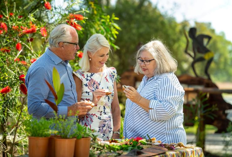 Two guests standing with a local Aboriginal guide in a garden while sampling local produce, Dale Tilbrook Experiences, Caversham, Perth © Tourism Australia