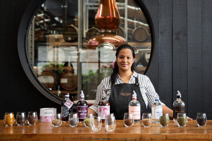 A bartender standing behind a bar with gins and botanicals, Four Pillars Gin, Healesville, Victoria © Visit Victoria
