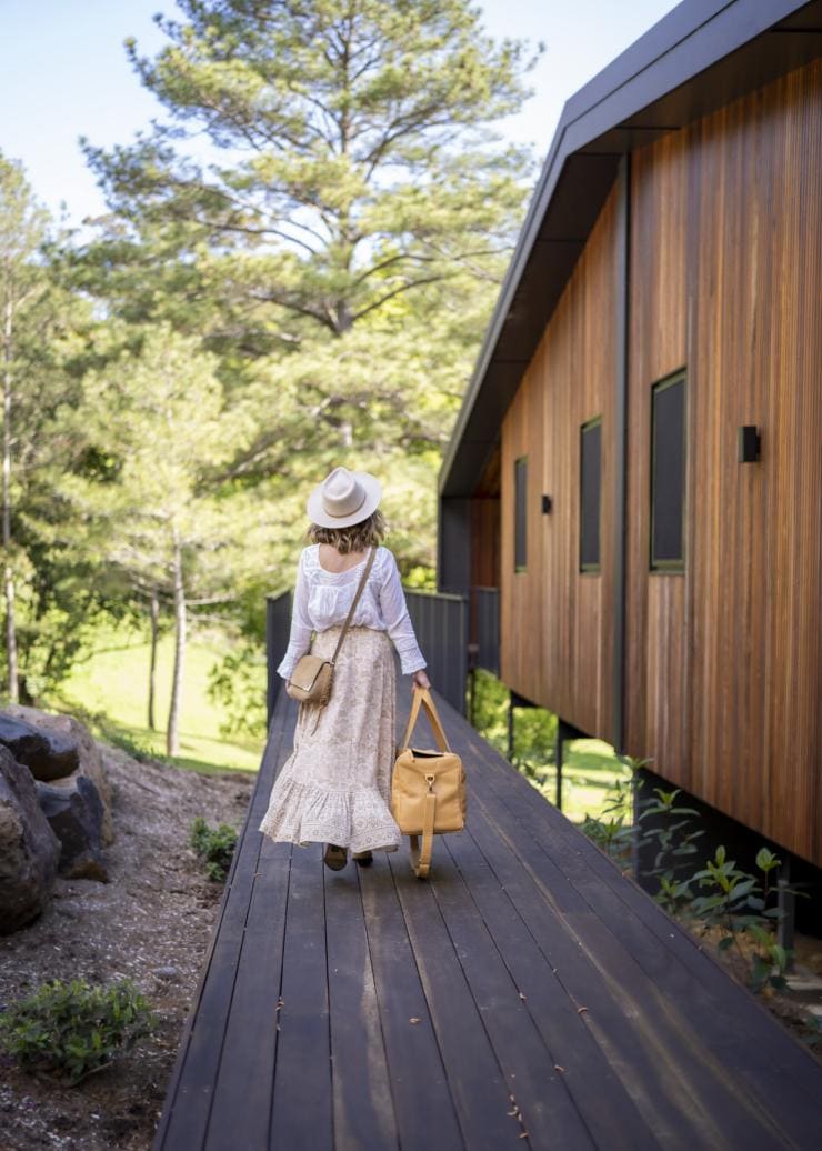 A woman arriving at her accommodation among bushland at Eden Health Retreat, Currumbin Valley, Queensland © Tourism and Events Queensland