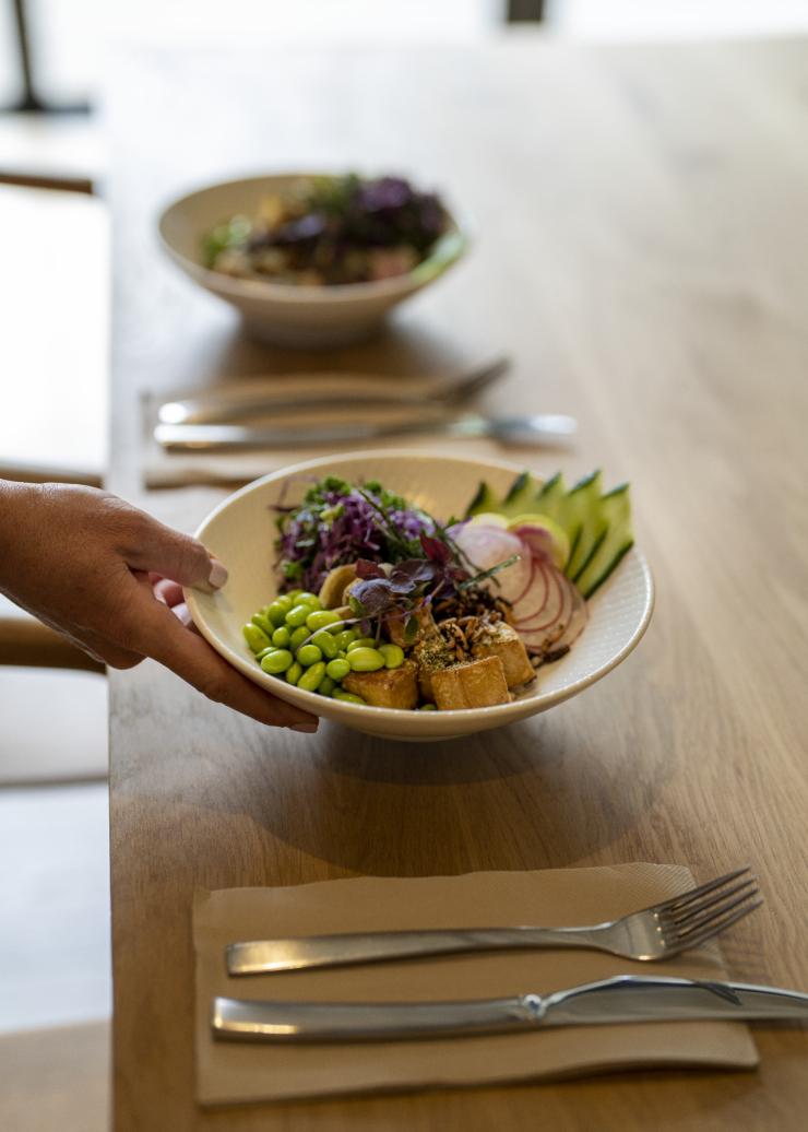 A hand placing a bowl of fresh produce down at a table at Eden Health Retreat, Currumbin Valley, Queensland © Tourism and Events Queensland