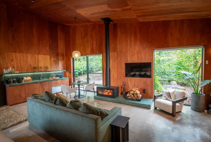 The interior of accommodation at Samadhi Retreat with a wood-burning fireplace beside green and wooden furnishings in Daylesford, Victoria © Samadhi Retreat
