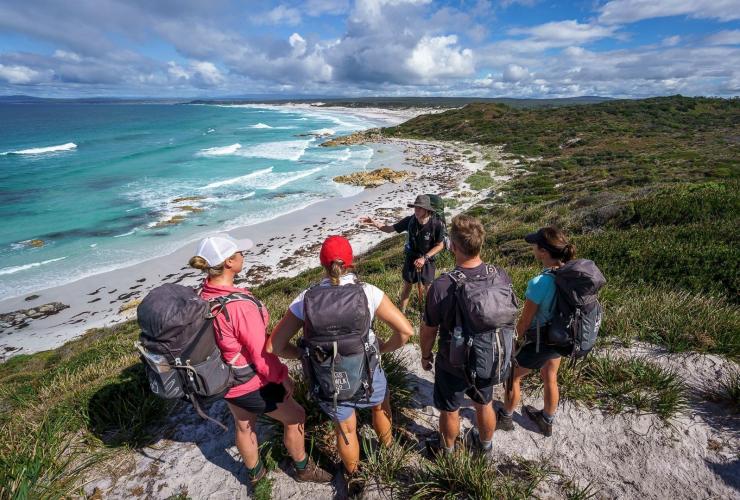 A group of people and a guide preparing for a hike across a white sand beach, Bay of Fires Signature Walk, Bay of Fires Conservation Area, Tasmania © Tourism Australia