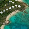 Aerial view over Lizard Island Resort accommodation amid the trees on the white sandy coastline of Lizard Island, leading to clear blue ocean in Queensland © Tourism and Events Queensland