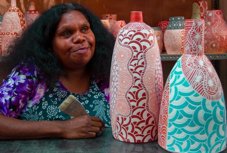 An Aboriginal artist seated beside ceramic artworks at Ernabella Art, Longitude 131, Uluru, Northern Territory © Longitude 131 