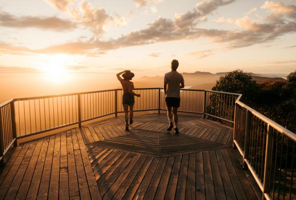 Two people walking towards the railing of Boroka Lookout with the sun lighting up the sky during sunrise, Grampians National Park, Victoria © Visit Victoria