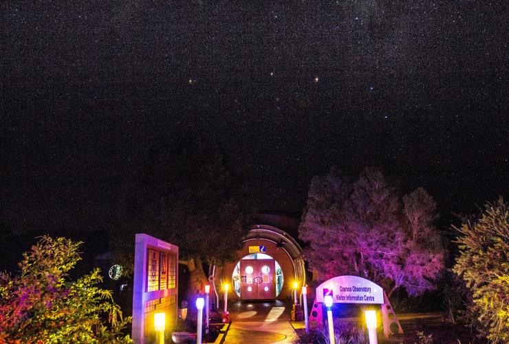 Exterior of the Cosmos Centre at night, lit up with colourful lights beneath a blanket of stars in Charleville, Queensland © Tourism and Events Queensland